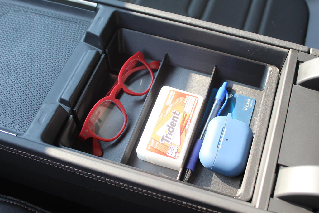 Squared Away Tray in a Rivian R2 center console, holding reading glasses, gum, a pen and a bank card