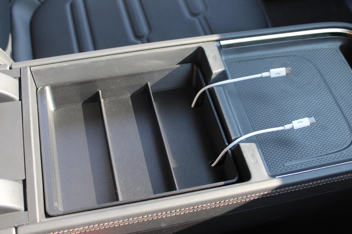 Empty Squared Away Tray in a Rivian R2 center console with two USB-C cables passing through the cord slot