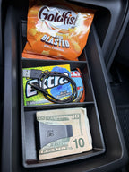 Slide-Out Drawer Tray in a Rivian R2 drawer holding crackers, gum with a charging cable, an energy bar and folded cash in a money clip